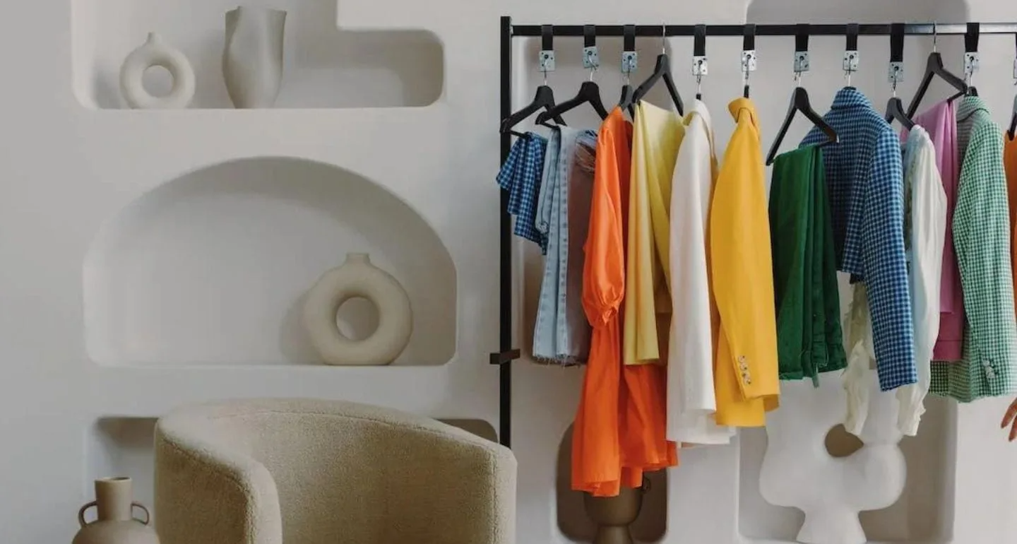 Colorful clothes on a rack with modern decor in a stylish, minimalist room interior.