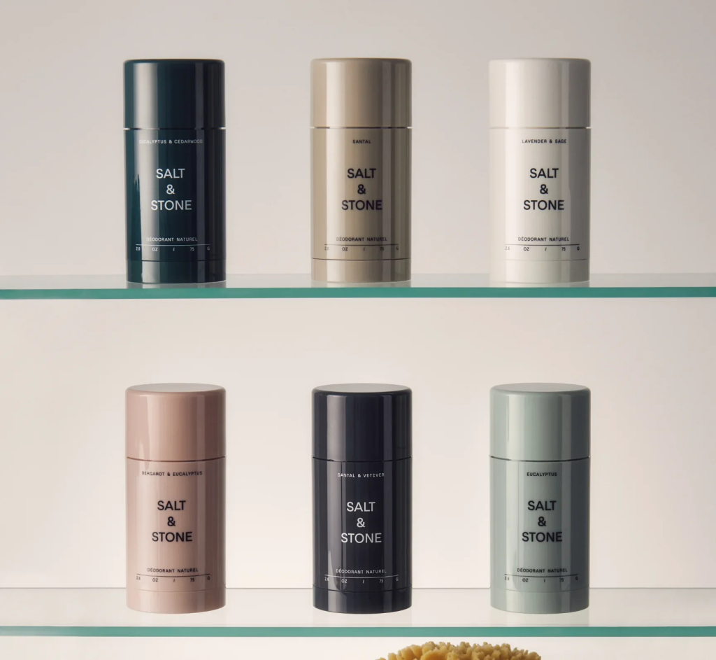 Salt & Stone deodorants in various scents on glass shelves, minimalist design, eco-friendly packaging