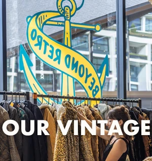 Woman browsing vintage clothing at Beyond Retro store with anchor logo on window