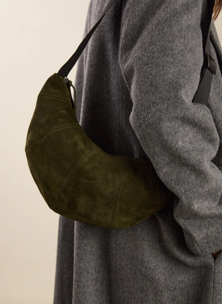 Model wearing a gray coat with an olive green suede shoulder bag.