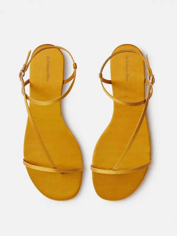 Stylish mustard yellow strappy flat sandals on a white background, perfect for casual summer fashion.